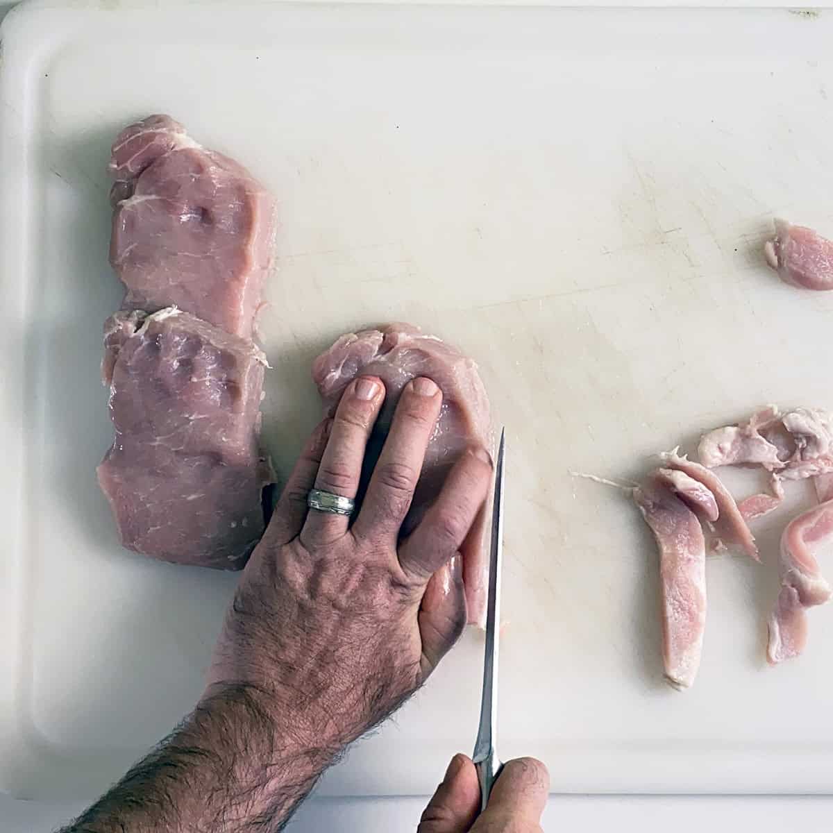 Trimming fat from pork cutlets.