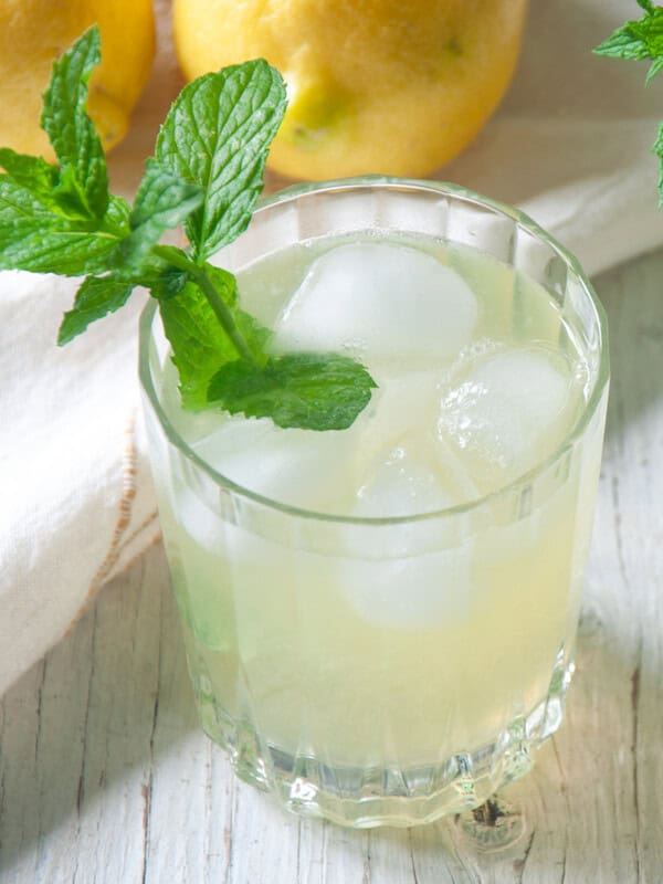 A single glass of Honey Lemonade with a sprig of mint in it.