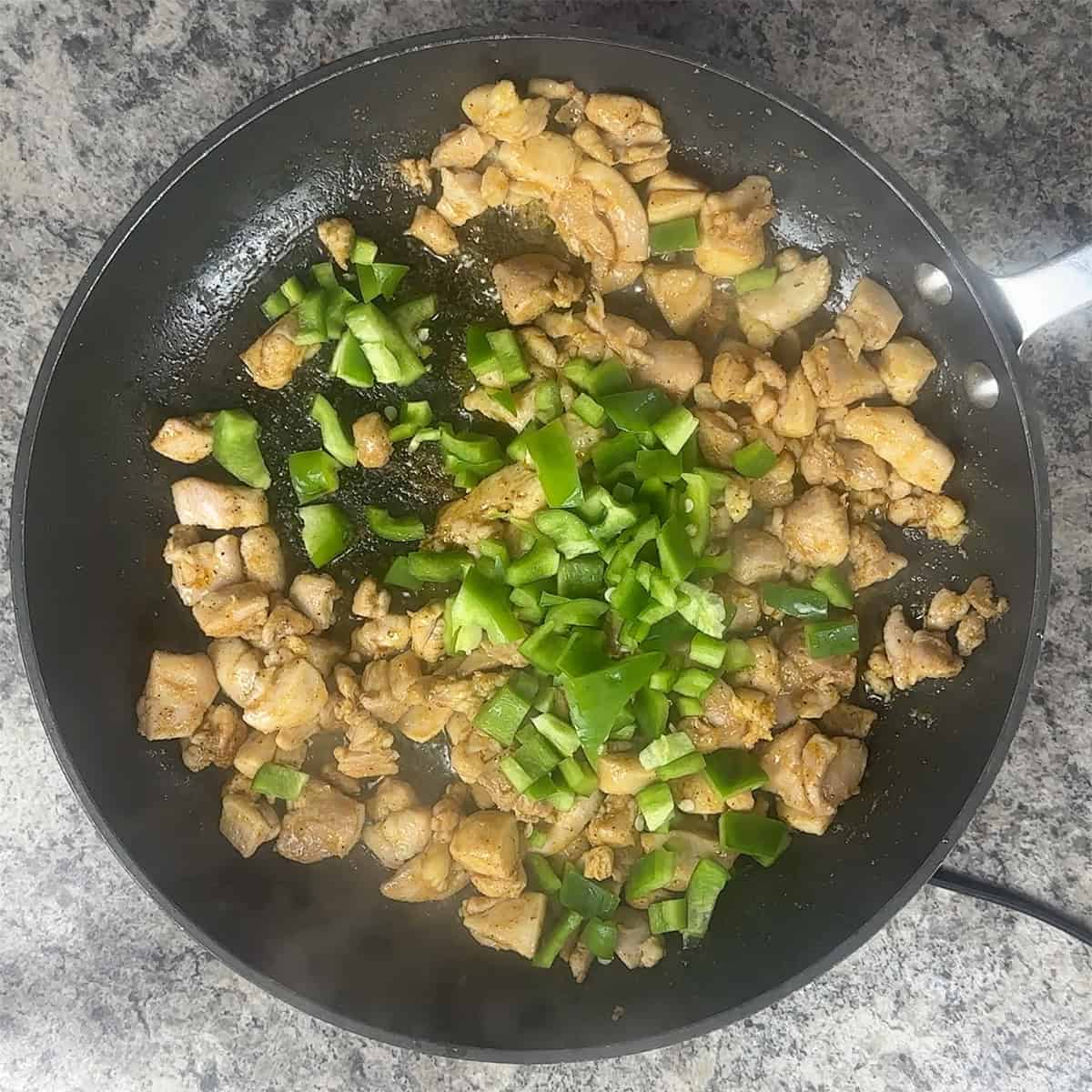 Chicken and pepper Chicken thigh and green bell pepper in a skillet.